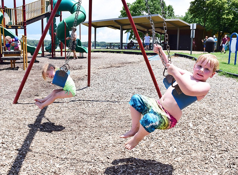 Staff Photo by Robin Rudd / Savannah Hayes and Jackson Daniel swing at the beachside playground at Chester Frost Park on June 25, 2020.  Savannah and Jackson were there with her great-grandmother, Jackie Pocius. Hamilton County reopened their playgrounds on June 24, 2020.  