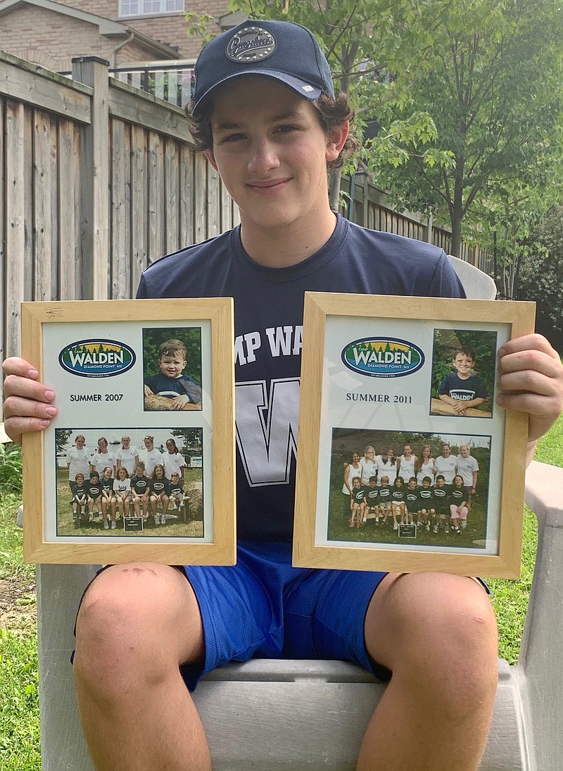 In this June 22, 2020, photo provided by Ashley Sederoff, 14-year-old Rory Sederoff holds framed photos of his previous summers at Camp Walden in 2007 and 2011 outside his home in Toronto. Sederoff would have been spending his 15th summer at Walden, and says he doesn't know what summer is without camp. (Ashley Sederoff via AP)



