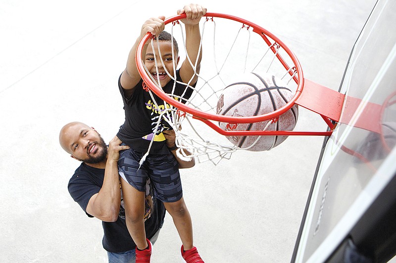 Staff photo by C.B. Schmelter / Jacques Irvin helps his son Jayden dunk during a photo shoot at his home on Monday, June 15, 2020 in Rossville, Ga.