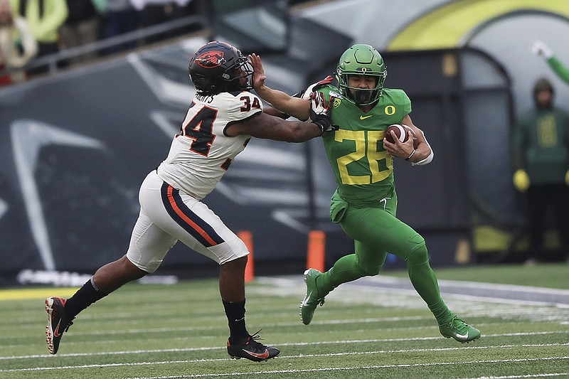 AP photo by Amanda Loman / Oregon running back Travis Dye tries to avoid Oregon State inside linebacker Avery Roberts during their rivalry matchup on Nov. 30, 2019, in Eugene, Ore.
