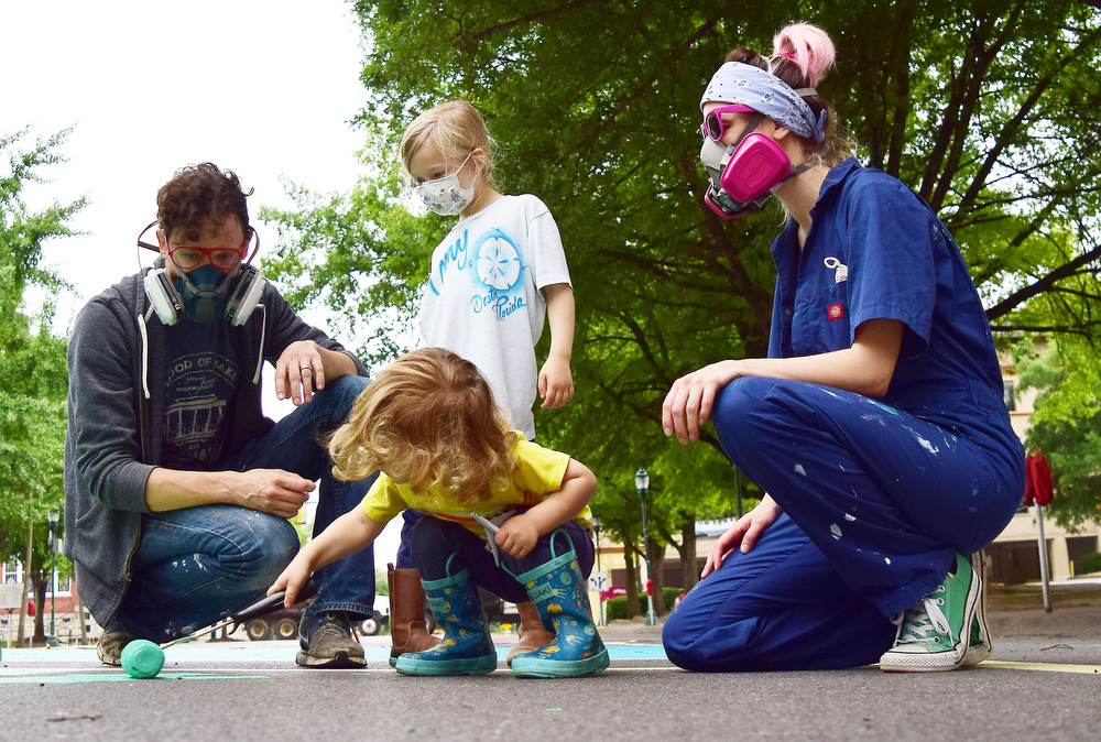 Staff Photo by Robin Rudd / Indy Brauer paints a section of the letter on Martin Luther King Jr. Blvd. as his mother father, Amy and Corban and sister, Briony, look on.