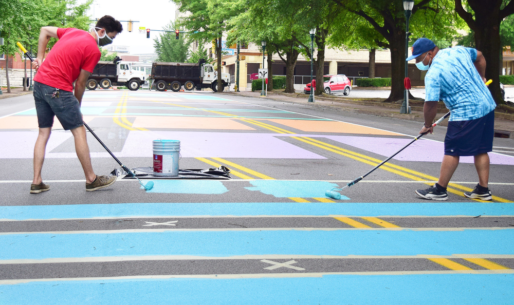 Staff Photo by Robin Rudd / From left, Chris Heintz and Nathan Stepney paint a letter on Martin Luther King Jr. Blvd..