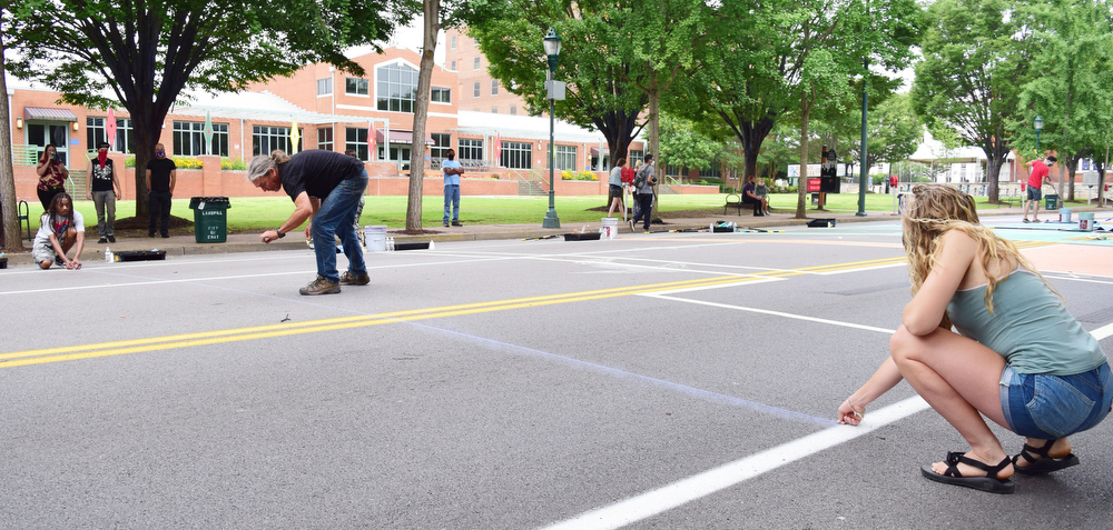 Staff Photo by Robin Rudd / The Artist SEVEN and Charolette Barron hold the chalk line as Michael Eastman pops it to work the outline for the letter "e."