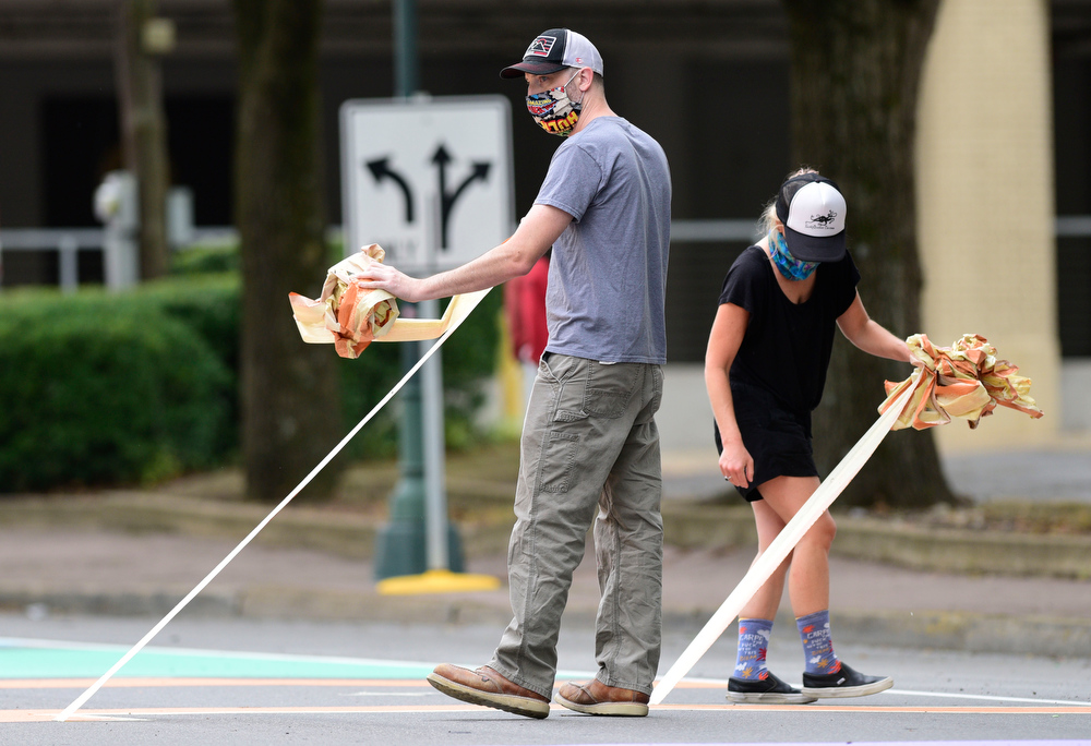 Staff Photo by Robin Rudd / Jesse Jungkurth and Meagan Shinn pull tape from a dried letter on Martin Luther King Jr. Blvd..