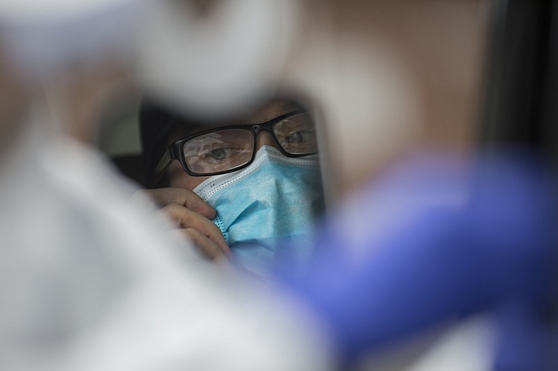 Staff photo by Troy Stolt / Trevor Pyke pulls his mask down while staring at the nasal swab held by a clinician before being tested for COVID-19 at a pop-up test site at New Hope Baptist Church by Cempa Community care on Wednesday, May 27, 2020 in Chattanooga, Tenn.