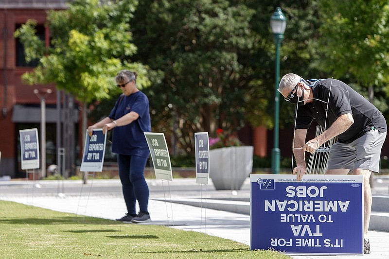 Staff photo by C.B. Schmelter / David, right, and Emily Anderson put up signs at Miller Park on Wednesday, June 17, 2020 in Chattanooga, Tenn. Members of the Engineering Association/IFPTE Local 1937 were protesting the announced layoffs of Tennessee Valley Authority IT workers.