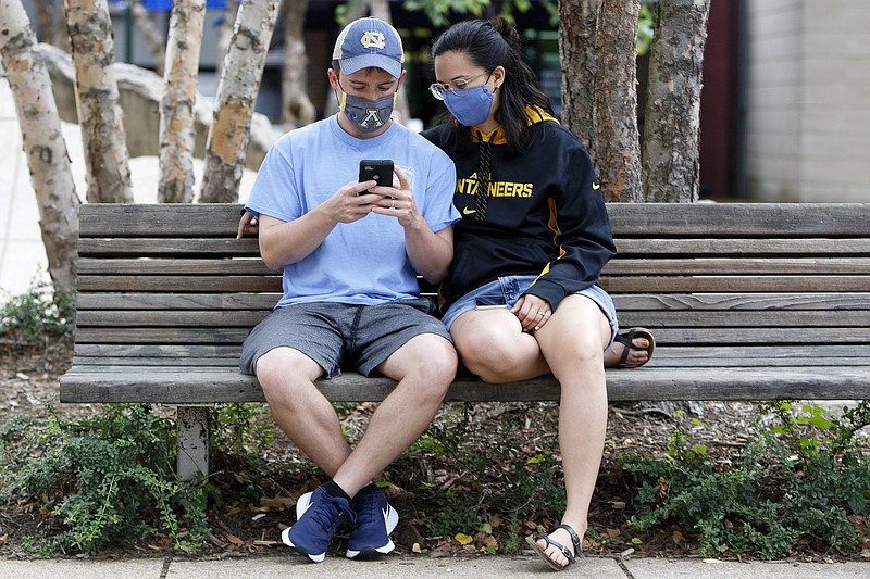 Staff photo by C.B. Schmelter / Jacque Heffner, right, looks on as her husband Trevor uses his phone to purchase tickets to the Tennessee Aquarium at the Aquarium Plaza on Tuesday, June 30, 2020 in Chattanooga, Tenn. The aquarium has dedicated hours when masks are required for visitors.