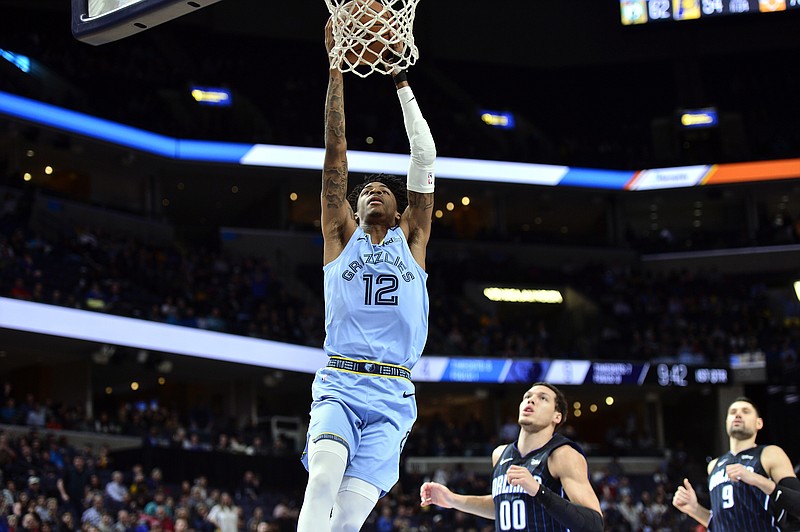 AP photo by Brandon Dill / Memphis Grizzlies guard Ja Morant dunks in front of Orlando Magic forward Aaron Gordon (00) and center Nikola Vucevic on March 10 in Memphis.
