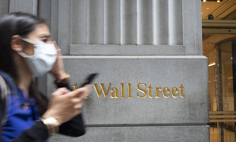 A woman wearing a mask passes a sign for Wall Street, Tuesday, June 30, 2020, during the coronavirus pandemic. (AP Photo/Mark Lennihan)


