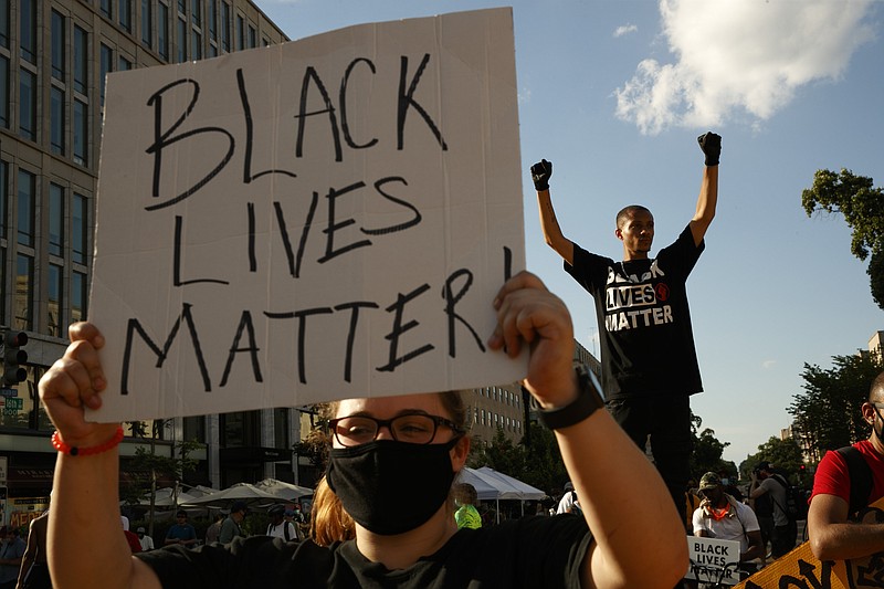 FILE - In this June 24, 2020, file photo, Antonio Mingo, right, holds his fists in the air as demonstrators protest in front of a police line on a section of 16th Street that's been renamed Black Lives Matter Plaza, in Washington. Thousands of Black activists from across the U.S. will hold the 2020 Black National Convention on Aug. 28, 2020, via livestream to produce a new political agenda that builds on the protests that followed George Floyd's death. Organizers of the gathering shared their plans with The Associated Press on Wednesday, July 1, ahead of an official announcement. (AP Photo/Jacquelyn Martin, File)