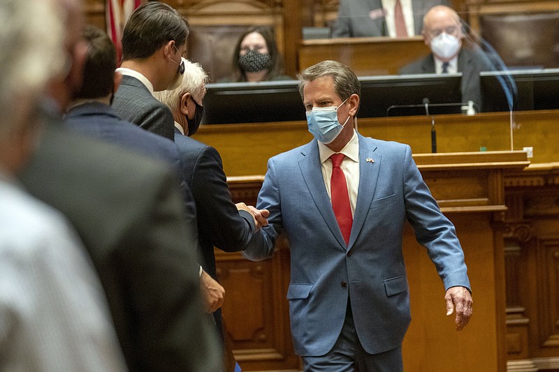 FILE - In this Friday, June 26, 2020, file photo, Georgia Gov. Brian Kemp is greeted as he visits the House Chambers on Sine Die, day 40, of the legislative session in Atlanta. Kemp says he hasn't yet weighed whether the state will take legal action against local governments trying to impose mask requirements. The Republican held a news conference Wednesday, July 1, 2020, before departing on a statewide tour to promote wearing a mask, but said he won't mandate it. (Alyssa Pointer/Atlanta Journal-Constitution via AP, File)