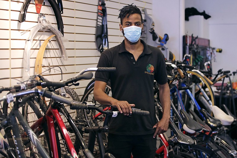 In this Wednesday, June 24, 2020, photograph, Noah Hicks, owner of Spokehouse Bikes in the Upham's Corner neighborhood of Boston, poses at his shop. Many from outside Boston have donated to and shopped at the store which was robbed and vandalized earlier in the month. (AP Photo/Charles Krupa)