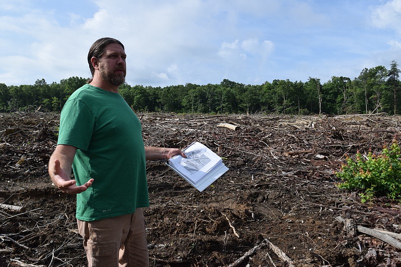 Staff photo by Ben Benton / Tennessee Heartwood and Sierra Club member Davis Mounger stands amid what remains from logging in recent years in Bledsoe State Forest on June 29, 2020. Mounger, holding a binder filled with state timber sale maps, said environmentalists are concerned about timbering going on in Bledsoe and other state forests that they say leads to single-species stands of undesirable plants and trees that crowd out more desirable species like oak and hickory.