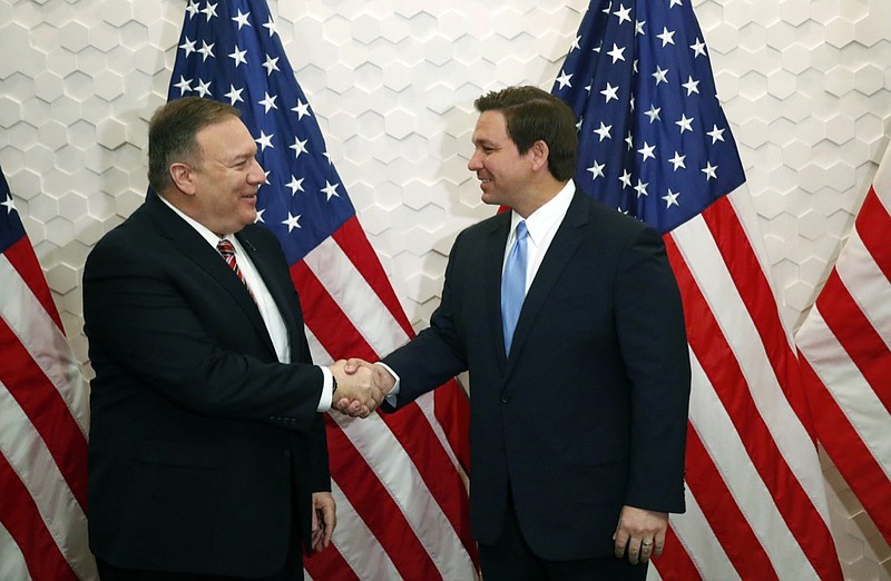 FILE - In this Jan. 23, 2020, file photo, Secretary of State Mike Pompeo, left, and Florida Gov. Ron DeSantis pose for a photo before participating in a roundtable discussion with Venezuelan exiles, in Miami. While President Donald Trump deals with his high-profile political difficulties in his high-profile ways, his Cabinet heads are fanning out to battleground states in November's presidential vote, trying to assure essential support blocs on all that the Trump administration is doing for them. (AP Photo/Wilfredo Lee, File)