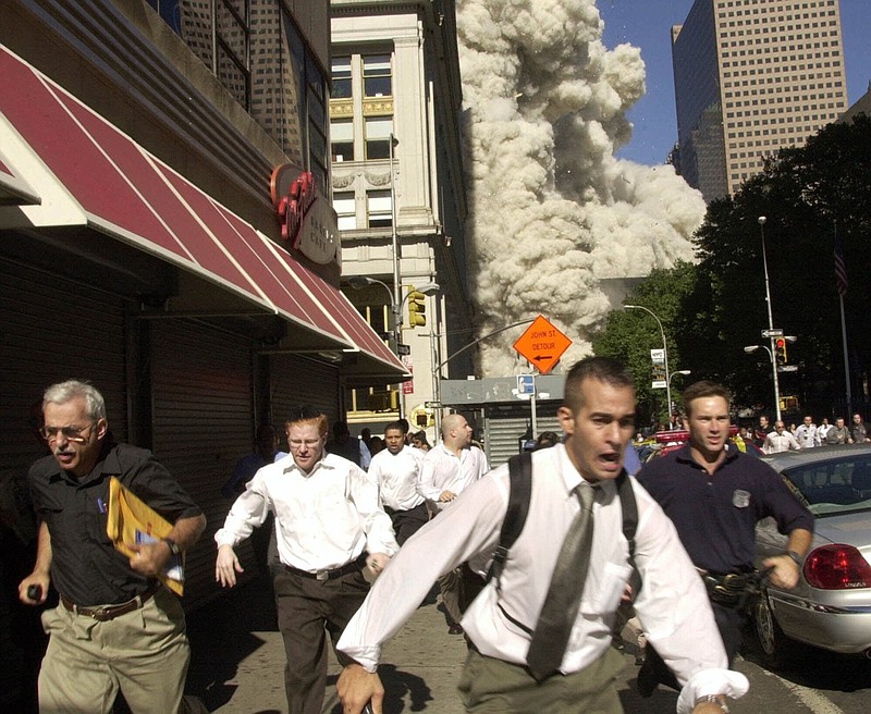 FILE - In this Sept. 11, 2001, file photo, people run from the collapse of one of the twin towers at the World Trade Center in New York. Stephen Cooper, far left, fleeing smoke and debris as the south tower crumbled just a block away on Sept. 11, has died from coronavirus, his family said, according to The Palm Beach Post. (AP Photo/Suzanne Plunkett, File)