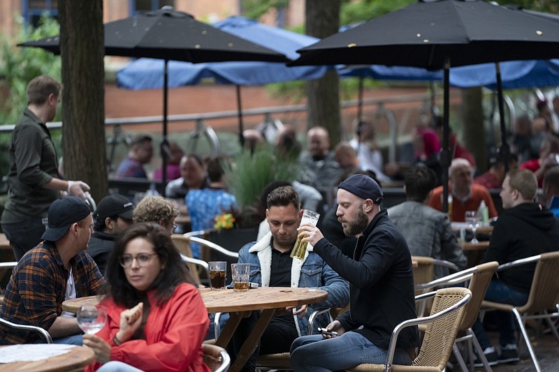 Members of the public are seen at a bar on Canal Street in Manchester's gay village, England, Saturday July 4, 2020. England is embarking on perhaps its biggest lockdown easing yet as pubs and restaurants have the right to reopen for the first time in more than three months. In addition to the reopening of much of the hospitality sector, couples can tie the knot once again, while many of those who have had enough of their lockdown hair can finally get a trim. (AP Photo/Jon Super)