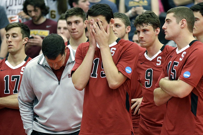 AP photo by Nam Y. Huh / Stanford men's volleyball coach John Kosty, second from left, looks down as players react after a 3-1 loss to Loyola on May 3, 2014, at Gentile Arena in Chicago. Stanford announced Wednesday that it is dropping 11 sports for financial reasons after the 2020-21 school year, including men's volleyball.