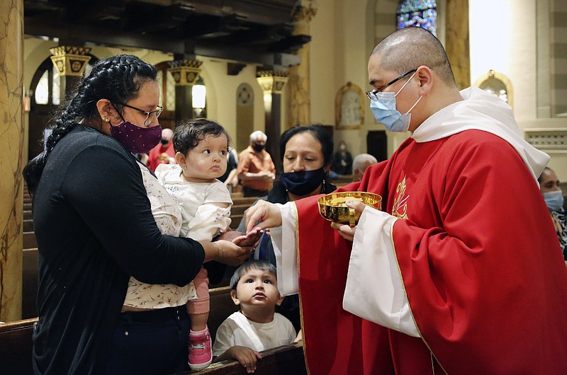 Parishioners receive the sacrament from the Rev. Luis Gabriel Medina during Communion at Saint Bartholomew Roman Catholic Church in the Queens borough of New York, Monday, July 6, 2020. This was the first in-person Mass at the church in almost four months. (AP Photo/Jessie Wardarski)