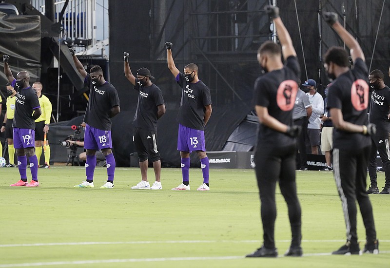 AP photo by John Raoux / Orlando City players, left, raise their fists in the air in solidarity with the group Black Players for Change during a protest against racial injustice before the start of a match against Inter Miami CF on Wednesday night in Kissimmee, Fla.