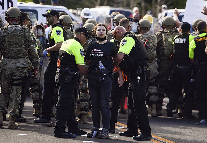 Photo by Erin Bormett/The Argus Leader via The Associated Press / The first person is arrested as protesters form a blockade of vans and bodies on the highway leading to Mount Rushmore on Friday, July 3, 2020, in Keystone, South Dakota. President Donald Trump spoke at Mount Rushmore National Memorial.