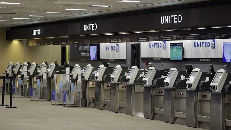 FILE - In this April 24, 2020 file photo, empty United Airlines ticket machines are shown at the Tampa International Airport in Tampa, Fla. United United Airlines will send layoff warnings to 36,000 employees - nearly half its U.S. staff - in the clearest signal yet of how deeply the virus outbreak is hurting the airline industry. United officials said Wednesday, July 8 that they still hope to limit the number of layoffs by offering early retirement, but they have to send notices this month to comply with a law requiring that workers get 60 days' notice ahead of mass job cuts. (AP Photo/Chris O'Meara, File)