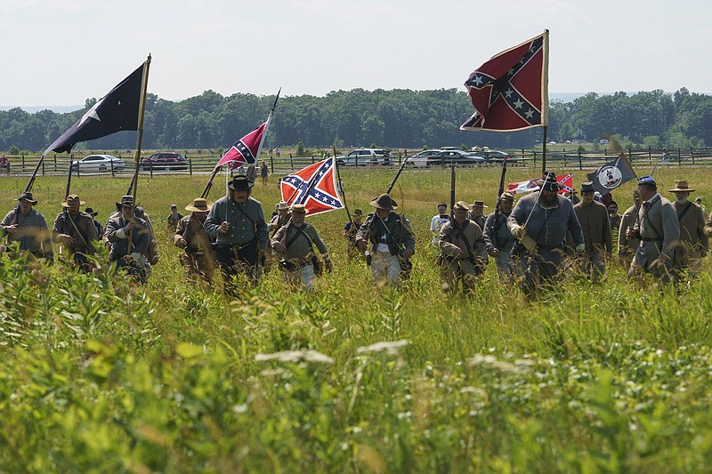 In this Friday, July 3, 2020, file photo, Civil War reenactors marching with Confederate battle flags during their reenactment of Pickett's Charge at Gettysburg National Military Park in Gettysburg, Pa. The banner, with its red field and blue X design, is the best known of the flags of the Confederacy, but the short-lived rebel nation also had other flags. (AP Photo/Carolyn Kaster, File)