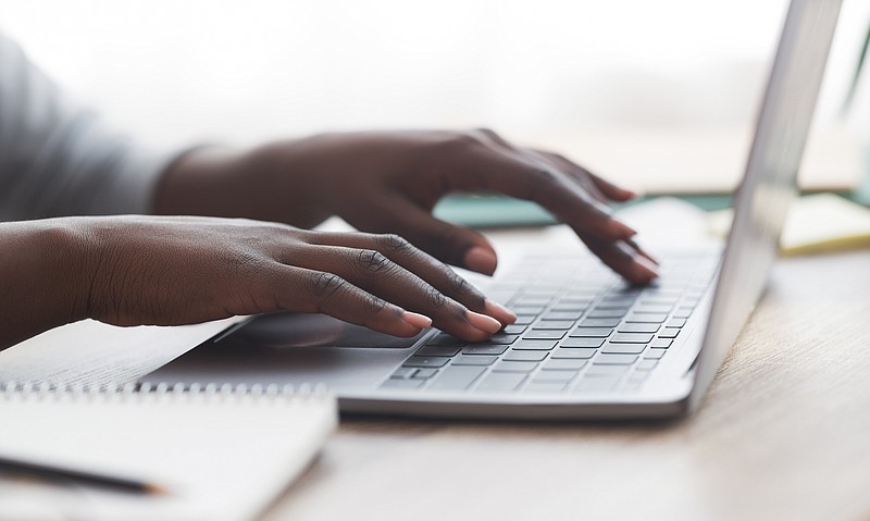 Black woman typing on laptop keyboard while working in office - stock photo business tile / Getty Images
