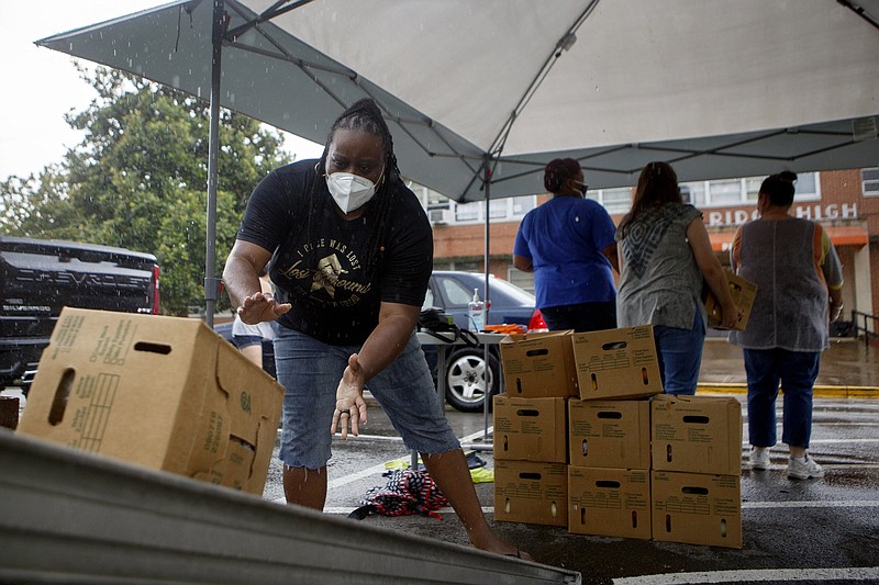 Staff photo by C.B. Schmelter / We Over Me co-founder Lakweshia Ewing, left, helps unload and stack produce boxes at We Over Me's "Pop-Up Produce Stand" at East Ridge High School on Thursday, July 9, 2020 in East Ridge, Tenn. We Over Me provided fresh produce boxes free of charge.