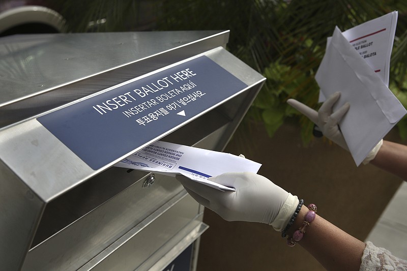 FILE - In this July 7, 2020, file photo a woman wearing gloves drops off a mail-in ballot at a drop box in Hackensack, N.J. The November election is coming with a big price tag as America faces the coronavirus pandemic. The demand for mail-in ballots is surging, election workers are in need of training and polling booths might have to be outfitted with protective shields. (AP Photo/Seth Wenig, File)


