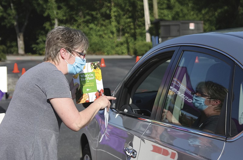 Sheri Arden from the University of Tennessee Extension Service hands out a pamphlet on healthy eating during a Senior Resource Expo at Home Instead Saturday July 11, 2020 in Maryville Tennessee. Packages with hand sanitizer, masks gloves, and senior directory were handed out aimed at the pandemic. (Tom Sherlin/The Daily Times via AP)


