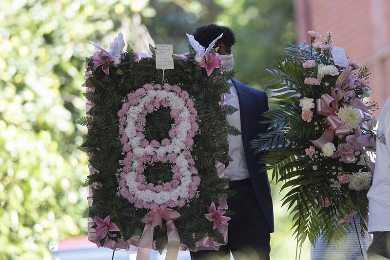 A man carries flowers into a viewing for 8-year-old Secoriea Turner, who was fatally shot in Atlanta on July 4th near the Wendy's site where Rayshard Brooks was killed the previous month Tuesday, July 14, 2020, in South Fulton, Ga. (AP Photo/John Bazemore)