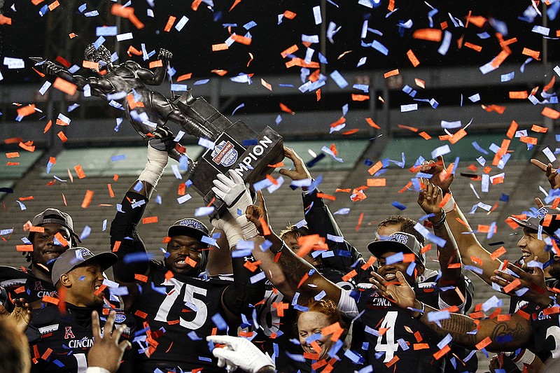 AP photo by Butch Dill / University of Cincinnati football players hoist the Birmingham Bowl trophy after beating Boston College 38-6 on Jan. 2 in Alabama.
