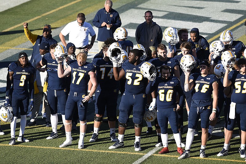 Staff photo by Robin Rudd / UTC football players hold up their helmets as the band plays the alma mater after a 35-20 loss to Furman on Nov. 2, 2019, at Finley Stadium.