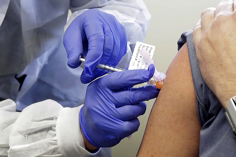 In this March 16, 2020 file photo, a subject receives a shot in the first-stage safety study clinical trial of a potential vaccine by Moderna for COVID-19, the disease caused by the new coronavirus, at the Kaiser Permanente Washington Health Research Institute in Seattle. Britain, the United States and Canada accused Russia on Thursday July 16, 2020, of trying to steal information from researchers seeking a COVID-19 vaccine. (AP Photo/Ted S. Warren, File)