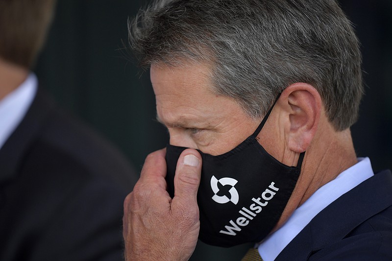 Georgia Gov. Brian Kemp adjusts his mask prior to a bill signing at Wellstar Kennestone Hospital where the hospital opened a new Emergency Room space, Thursday, July 16, 2020, in Marietta, Ga. Mayors in Atlanta and other Georgia cities deepened their defiance of Gov. Kemp on Thursday, saying they want their requirements for people to wear masks in public to remain in place, even after the Republican governor explicitly forbade cities and counties from mandating face coverings.(AP Photo/Mike Stewart)