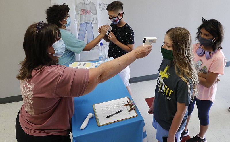 In this Tuesday, July 14, 2020 file photo, Amid concerns of the spread of COVID-19, teachers check students before a summer STEM camp at Wylie High School in Wylie, Texas. Not knowing if children are infected makes it difficult for schools to reopen safely, many experts say. Scarce data on whether infected children _ including those without symptoms _ easily spread the disease to others complicates the issue, said Jeffrey Shaman, a Columbia University infectious disease specialist. (AP Photo/LM Otero)
