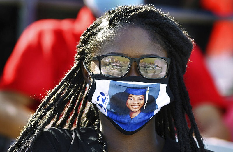 Sierra Black wears a protective mask with the photograph of her cousin, Cheyenne Cobb, who was in the 2020 graduating class, in the stands of TIAA Bank Field, Friday morning, July 17, 2020, in Jacksonville, Fla., during the coronavirus delayed graduation ceremony for the Frank H. Peterson Academies of Technology. (Bob Self/The Florida Times-Union via AP)