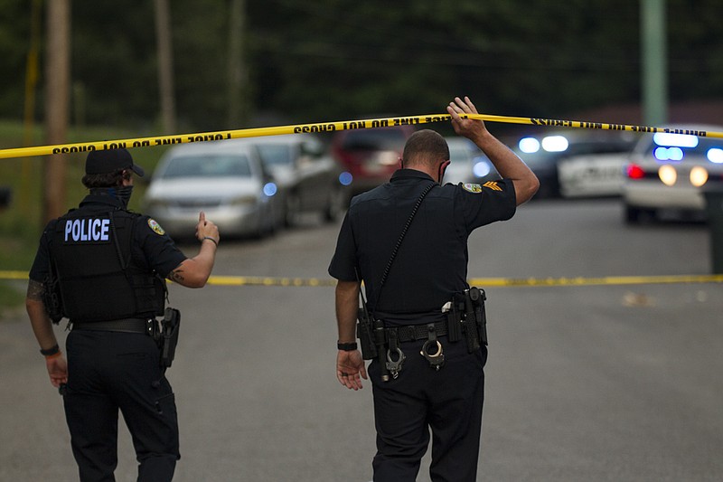 Staff photo by Troy Stolt / Chattanooga Police officers walk underneath police lines set up on the 4000 block of Kemp Drive, where a man was shot on Saturday, July 18, 2020 in Chattanooga, Tenn.