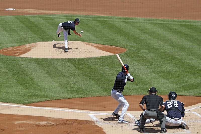 An umpire crouches as New York Yankees starting pitcher Gerrit Cole, top, delivers to Kyle Higashioka, front left, during an intrasquad game in baseball summer training camp Sunday, July 12, 2020, at Yankee Stadium in New York. (AP Photo/Kathy Willens)