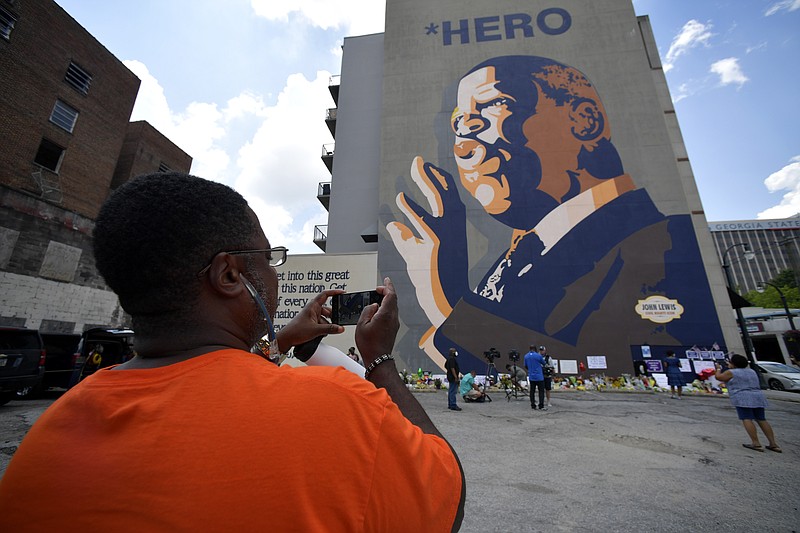 People gather at a make-shift memorial near the home of Rep. John Lewis, D-Ga., Sunday, July 19, 2020, in Atlanta. Lewis, who died Friday at age 80, was the youngest and last survivor of the Big Six civil rights activists who organized the 1963 March on Washington, and spoke shortly before the group's leader, Rev. Martin Luther King Jr., gave his "I Have a Dream" speech to a vast sea of people. (AP Photo/Mike Stewart)