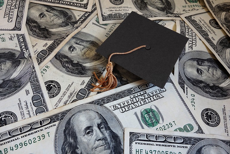 Miniature graduation cap on assorted cash student loan money tile college tile cost / Getty Images
