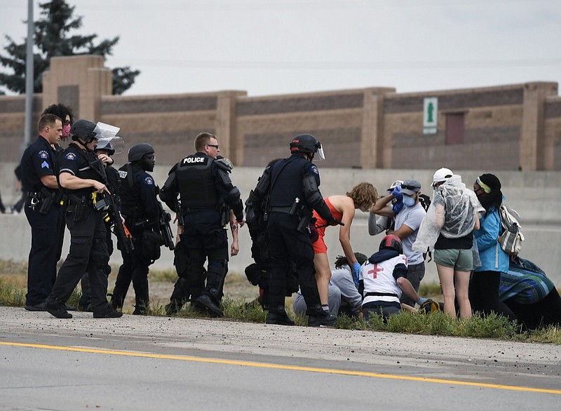 Aurora Police officers and protest medics attend to an injured demonstrator who police believe was shot by a fellow protester while on Interstate 225, Saturday, July 25, 2020, in Aurora, Colo., during a protest against racial injustice and the death of Elijah McClain, who was stopped by police while walking down an Aurora street in August 2019 after a 911 caller reported him as suspicious. (Andy Cross/The Denver Post via AP)