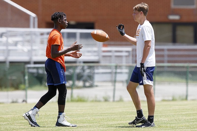 Staff photo by C.B. Schmelter / JJ Janow tosses the ball to Kam Clay while running routes at East Ridge High School's Raymond James Stadium on June 15. Clay and Janow are both sophomores.