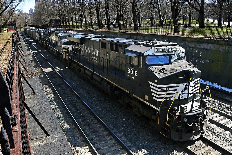 FILE- In this March 26, 2018, file photo, a Norfolk Southern freight train rolls through downtown Pittsburgh. Norfolk Southern Corp.'s second-quarter profit fell 46% as the railroad hauled 26% less freight because of the coronavirus outbreak's impact on the economy. The railroad said Wednesday, July 29, 2020 it earned $392 million, or $1.53 per share, during the quarter. (AP Photo/Gene J. Puskar, File)