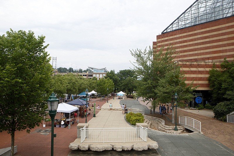 Staff photo by C.B. Schmelter / Booths are seen as people mingle in Aquarium Plaza at the Chattanooga River Market's grand opening in late June.