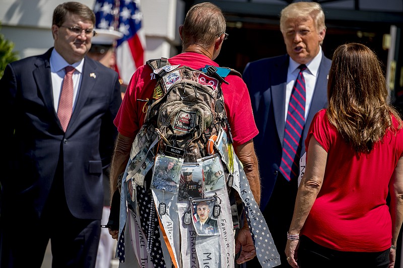 Photographs of soldiers are clipped to the backpack of Terry Sharpe, center, known as the "Walking Marine" as he is greeted by President Donald Trump, second from right, Veterans Affairs Secretary Robert Wilkie, left, and Karen Pence, the wife of Vice President Mike Pence, right, at the White House in Washington, Monday, July 27, 2020. Sharpe has walked from Summerfield, N.C., to Washington to raise awareness of the current veteran suicide rate. (AP Photo/Andrew Harnik)


