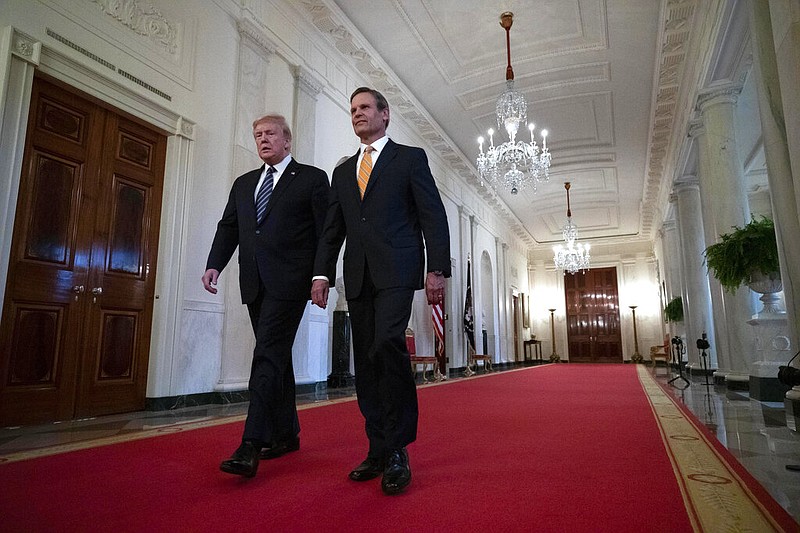 President Donald Trump, left, accompanied by Gov. Bill Lee, R-Tenn., walks in the Cross Hall to speak about protecting seniors, in the East Room of the White House, Thursday, April 30, 2020, in Washington. (AP Photo/Alex Brandon)