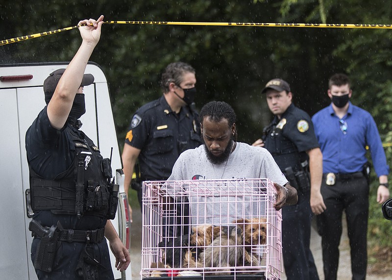 Staff photo by Troy Stolt / A man carries three small Yorkshire terriers out of a home on the 2900 block of Lightfoot Mill Road where a homicide occurred on Thursday, July 30, 2020 in Chattanooga, Tenn.