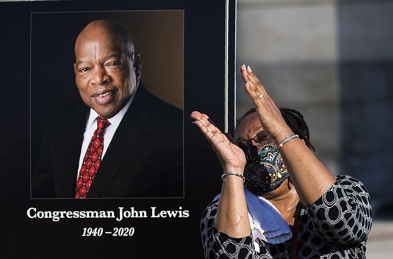 Jaquenette Ferguson from Oxon Hill, Md., gestures as she gets her picture taken beside a portrait of the late Rep. John Lewis, D-Ga., near the East Front Steps of the U.S. the Capitol, Tuesday, July 28, 2020, in Washington. (AP Photo/Manuel Balce Ceneta)