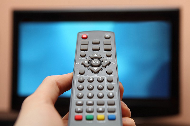 Tv remote control with television in background. / Getty Images/iStock/gielmichal